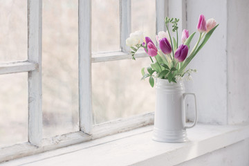 Fototapeta na wymiar beautiful tulips on old white windowsill