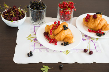 Sweet rolls. Berries. Fresh croissants and ripe red currants, black currants, cherries.