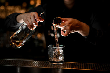 Bartender preparing alcoholic cocktail with ice at bar.