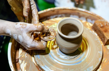 Professional potter makes a pot on a pottery wheel. Hands of a potter.