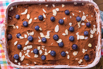 Tiramisu. Traditional italian dessert on white plate. Delicious dessert for breakfast, with blueberries, the bright colors of the dishes. Copy space. Top view