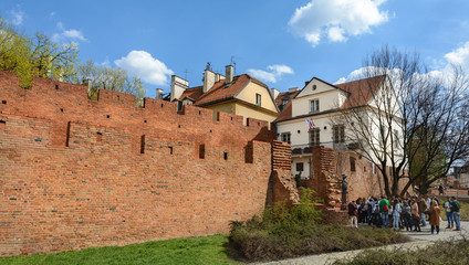 Fototapeta na wymiar Warsaw Old city. Houses and city wall. Earthworks. Red brick city wall. Small street, Rycerska street, in the medieval old city in Warsaw. The oldest historical district of Warsaw
