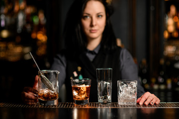 bar counter with variety of glasses with ice and alcoholic drinks.