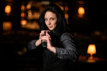 Young beautiful brunette barman girl holding shaker.
