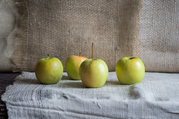 Still life with green apples on the table. Apples lie on a background of drapery