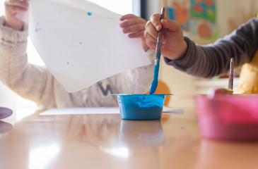 Children painting pictures at table indoors