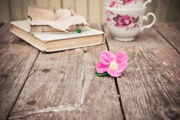 Obraz na płótnie Canvas Pink Flowers and old books and tea cups on rustic wooden table. Vintage Floral background.