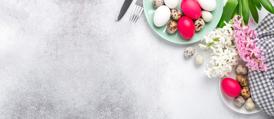Easter composition. Green mint plate, easter eggs, pink and white hyacinth, silver cutlery on stone background. Copy space. Top view