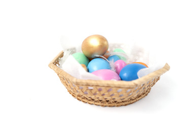 Golden, pink, blue, green, orange eggs in the wicker basket on the white background. Copy space. Place for text and design. Happy Easter. 