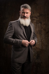 Portrait of a Middle Age Man with Beard and Mustache Posing in Formal Wear on a Dark Backdrop, selective focus