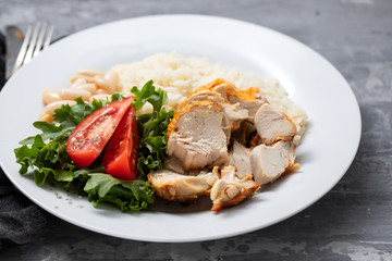 grilled chicken breast with salad and boiled rice on white plate