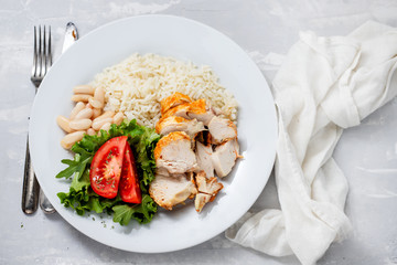 grilled chicken breast with salad and boiled rice on white plate
