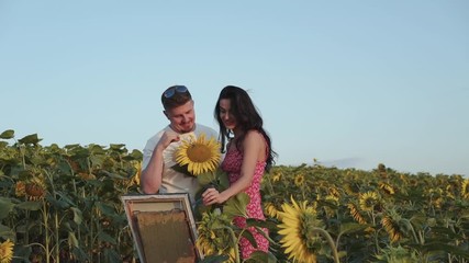 Pretty female artist painting, her man presents a sunflower and they have a fun