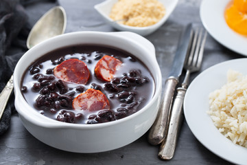 typical brazilian food black beans with smoked sausages in white bowl