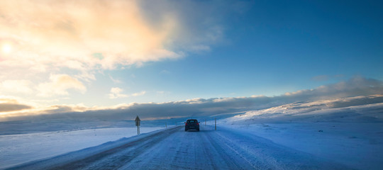 Following a car on a never-ending snow-covered road in Iceland