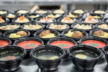 Row of plastic disposable lunch box with healthy natural food. Soups, cream soup, main course with side dish, salads. Food delivery. Lunch in the office.