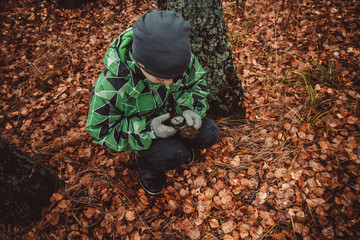 The child is guided by a compass in the woods. Autumn. A teenage boy got lost. Look for a way out of the woods. Lost alone in a strange place.