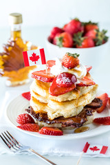 Close up of a stack of pancakes with strawberries and maple syrup for Canada Day.