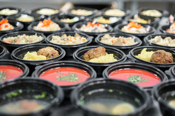 Food delivery. Different in plastic disposable lunch box with healthy natural food. Chicken broth, mashed soup, mashed potatoes with cutlet, seafood pasta, salads, pilaf with a fresh bun.