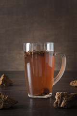 Organic Chaga mushrooms hot coffee in glass cup. Trendy healthy clean eating beverage on dark.