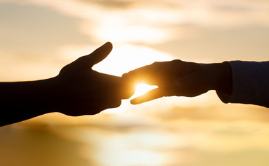 Giving a helping hand. Rescue, helping gesture or hands. Two hands silhouette on sky background,...