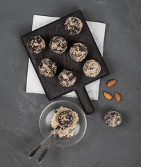 Candy balls energy from dried prunes, dates and almonds, cashews, walnuts, sprinkled with almond crumbs on a wooden Board on a light background top view