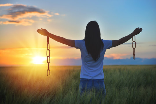 Woman feeling free in a beautiful natural setting, in what field at sunset. Free from chains