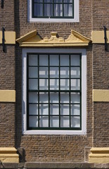 Baroque window with broken volute pediment on the brick facade of a residential house, old town of Goes in the Netherlands