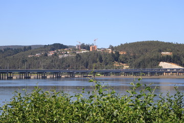 puente en rio con cerros de fondo