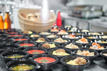 Food delivery. Different in plastic disposable lunch box with healthy natural food. Chicken broth, mashed soup, mashed potatoes with cutlet, seafood pasta, salads, pilaf with a fresh bun.