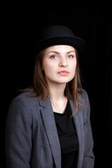 cute young girl in hat and gray jacket on black background