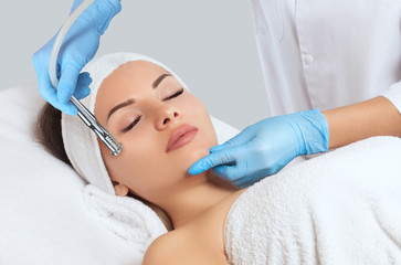 Naklejka premium The cosmetologist makes the procedure Microdermabrasion of the face skin of a beautiful woman in a beauty salon.Cosmetology and professional skin care.
