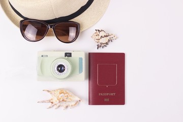 Flat lay travel concept. Set of items for tourist on white background. Top view travel mockup white table with hat, sunglasses, vintage camera, seashells and passport. Copy space.