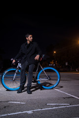 young manin black lying on his bike in a dark park at night 