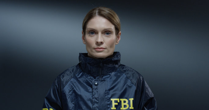 Close up of the young pretty Caucasian woman, FBI worker rising her face and siling happily straight to the camera. Portrait.