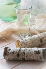 Glasse of birch sap on shabby wooden table with birch branch