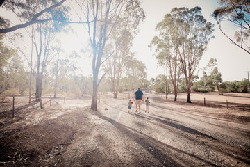 Father and sons walking along bush track holding hands