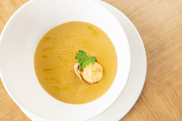 Cream-soup with porcini mushroom with croutons on wooden table. Restaurant menu