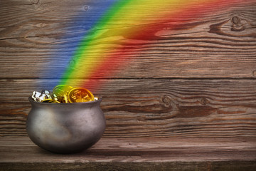 Rainbow pot of gold on old wooden background. St. Patrick's day symbol