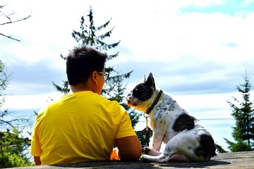 Man Sitting With Dog Against Sky