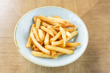 French fries in a bowl on a wooden background