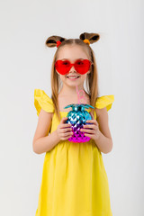 happy child girl in sunglasses holding a glass with a cocktail on a white background isolate
