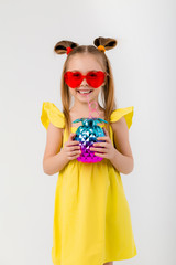 happy child girl in sunglasses holding a glass with a cocktail on a white background isolate