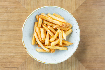 French fries in a bowl on a wooden background