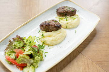 Delicious juicy meat cutlets, mashed potatoes sprinkled with greens and fresh healthy salad of tomatoes and lettuce leaves.