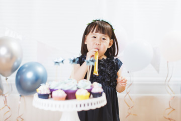 toddler girl playing at her birthday party against window background