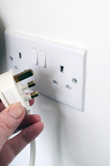 Hand putting a plug in/out of a socket