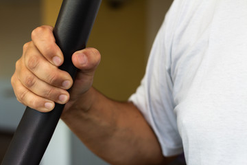 Close up of a man working out at the gym. Man's hand taking an exercise machine.