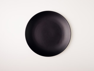 Empty black matte ceramic round plate isolated on white background