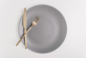 Goolden fork and knife on a empty plate on white background